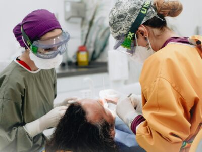 Two healthcare professionals perform a dental procedure in a medical examination room.